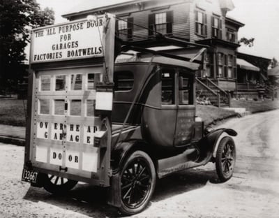 C.G. Johnson driving his car to promote garage doors